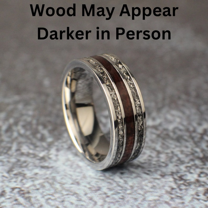 Puede incluir: Un anillo de plata con una incrustaci&oacute;n de madera marr&oacute;n oscura y una textura moteada plateada. El texto "Wood May Appear Darker in Person" es visible sobre el anillo.