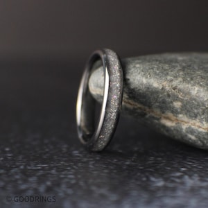 4mm tungsten ring with crushed moonstone inlay standing upright against a natural stone background with soft lighting