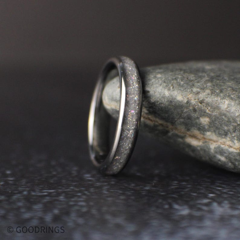 4mm tungsten ring with crushed moonstone inlay standing upright against a natural stone background with soft lighting