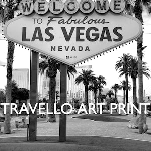 May include: Black and white art print of the iconic "Welcome to Fabulous Las Vegas Nevada" sign. The sign is set against a backdrop of palm trees and buildings. The words "Travello Art Print" are at the bottom.