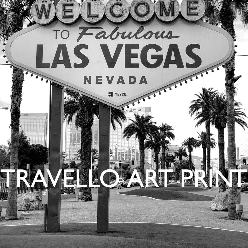 May include: Black and white art print of the iconic "Welcome to Fabulous Las Vegas Nevada" sign. The sign is set against a backdrop of palm trees and buildings. The words "Travello Art Print" are at the bottom.