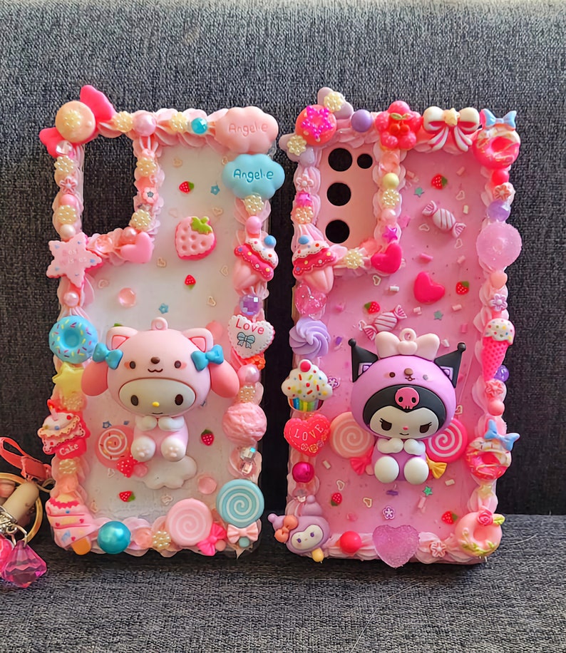May include: Two pink and white phone cases decorated with colorful candy, sprinkles, and cartoon characters. The cases feature the words "Love" and "Angele" in pink and white.