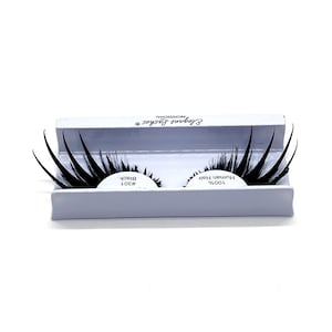 Può includere: Un paio di ciglia finte nere in una scatola bianca. La scatola riporta la scritta "100% Capelli Umani" e "Elegant Lashes Professional".