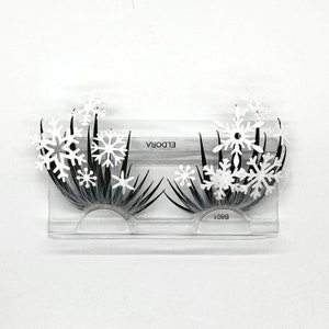 May include: A pair of false eyelashes with snowflake embellishments. The eyelashes are packaged in a clear plastic case with the brand name "ELDORA" and the product code "B801" printed on the case.