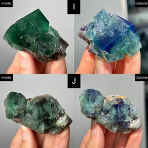 May include: Two sets of raw fluorite crystal clusters labeled I and J, showing variations in color between indoor and outdoor lighting. The crystals display deep green, blue, and purple hues with geometric, cubic formations and rough, textured bases.
