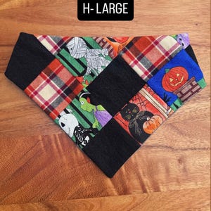 Puede incluir: Un pa&ntilde;uelo triangular para mascotas con un dise&ntilde;o de patchwork de cuadrados de tela negra que se alternan con cuadrados estampados con motivos de Halloween que incluyen una momia, una calabaza, un gato negro y un esqueleto, texto H-LARGE.