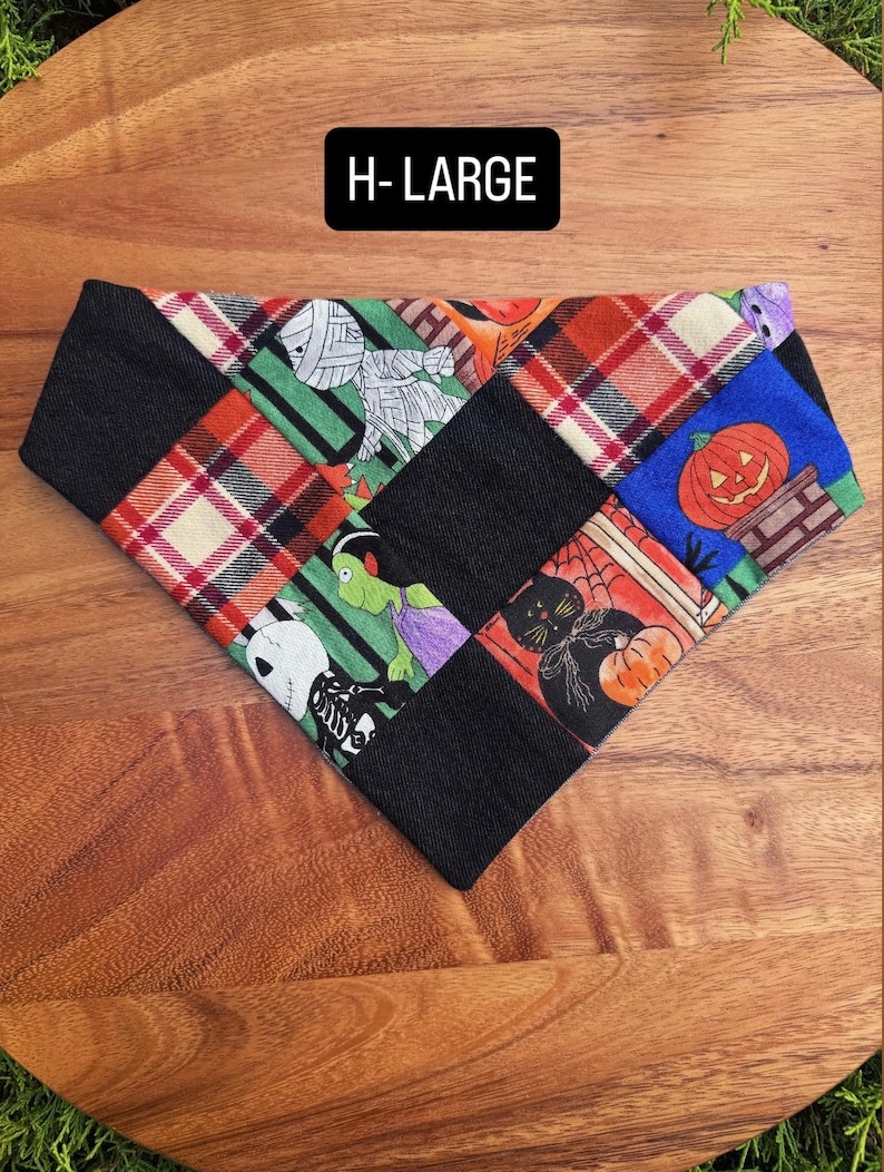 Puede incluir: Un pa&ntilde;uelo triangular para mascotas con un dise&ntilde;o de patchwork de cuadrados de tela negra que se alternan con cuadrados estampados con motivos de Halloween que incluyen una momia, una calabaza, un gato negro y un esqueleto, texto H-LARGE.