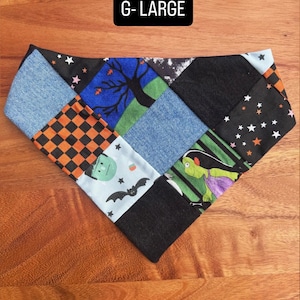 Puede incluir: Un pa&ntilde;uelo triangular para mascotas con un dise&ntilde;o de patchwork de varias telas, incluyendo mezclilla azul, tela negra y estampados con motivos de Halloween como murci&eacute;lagos, estrellas, un &aacute;rbol y un monstruo. El texto G-LARGE est&aacute; impreso en la tela.
