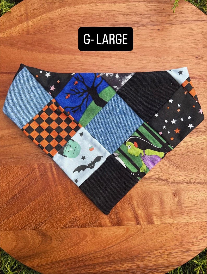 Puede incluir: Un pa&ntilde;uelo triangular para mascotas con un dise&ntilde;o de patchwork de varias telas, incluyendo mezclilla azul, tela negra y estampados con motivos de Halloween como murci&eacute;lagos, estrellas, un &aacute;rbol y un monstruo. El texto G-LARGE est&aacute; impreso en la tela.