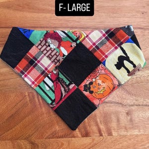 Puede incluir: Un pa&ntilde;uelo triangular para mascotas con un dise&ntilde;o de patchwork de cuadrados de tela negra que se alternan con estampados de Halloween, incluyendo un gato negro, una calabaza y un personaje. El texto F-LARGE aparece en una etiqueta negra.