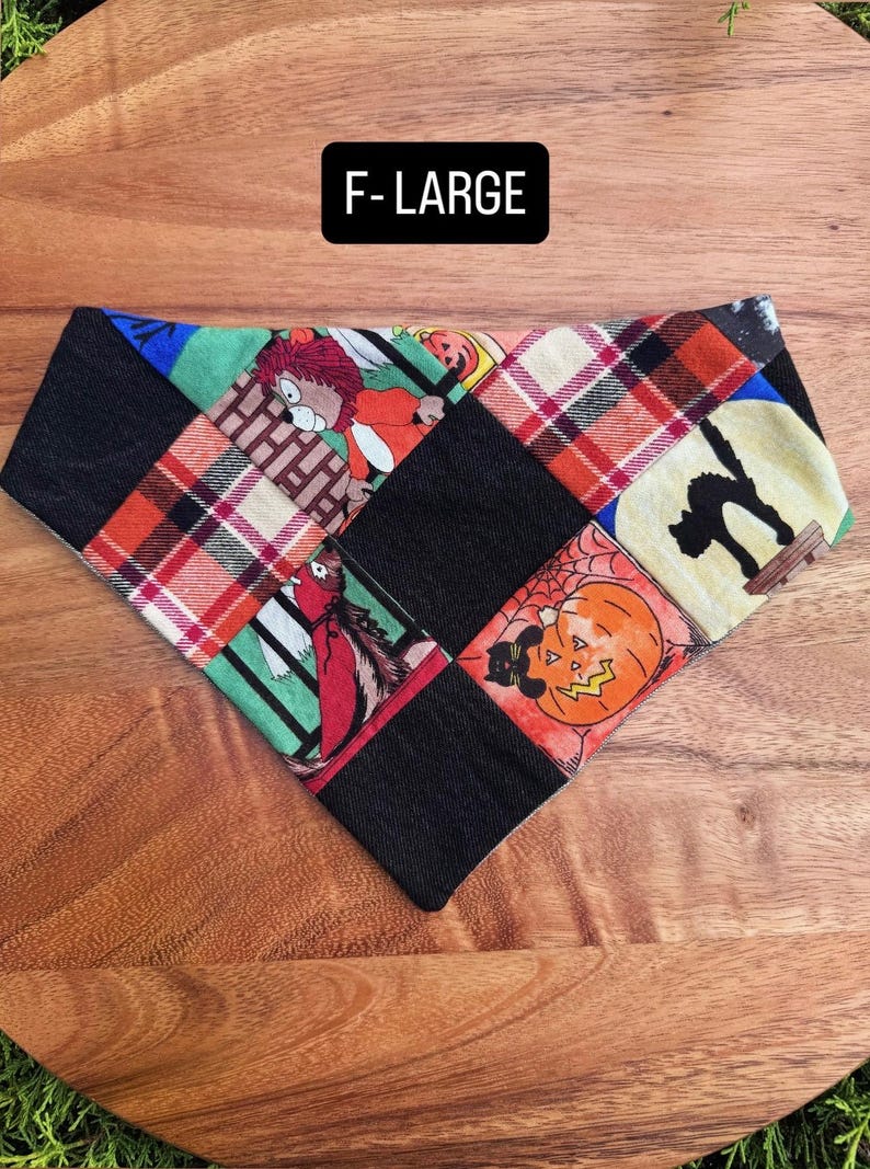 Puede incluir: Un pa&ntilde;uelo triangular para mascotas con un dise&ntilde;o de patchwork de cuadrados de tela negra que se alternan con estampados de Halloween, incluyendo un gato negro, una calabaza y un personaje. El texto F-LARGE aparece en una etiqueta negra.