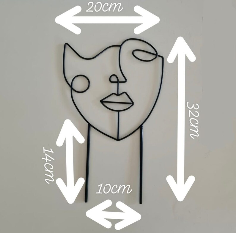 Puede incluir: Escultura de alambre de metal negro de una cara estilizada. La escultura tiene 20 cm de ancho, 32 cm de alto y 14 cm de profundidad. La escultura est&aacute; sobre un fondo blanco.