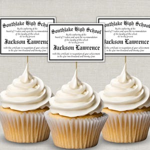 May include: Three cupcakes with white frosting and diploma toppers. The toppers read "Southlake High School" and "Jackson Lawrence" with the year 2024. The cupcakes are in paper liners.