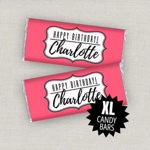 Könnte beinhalten: Zwei rechteckige Schokoriegel in leuchtend rosa Papier mit einem weißen dekorativen Rahmen, der den schwarzen Text HAPPY BIRTHDAY! Charlotte enthält. Eine schwarze Sternform in der Ecke zeigt den weißen Text XL CANDY BARS.