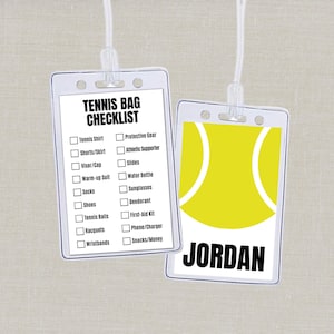 May include: Two clear plastic luggage tags. One tag features a tennis bag checklist with items like tennis shirt, shoes, and racquets. The other tag has a yellow tennis ball design and the name "JORDAN" in black.