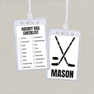 May include: Two clear plastic hockey bag tags with white cords. One tag has a checklist of hockey gear. The other tag has crossed hockey sticks, a puck, and the name "MASON" in black.