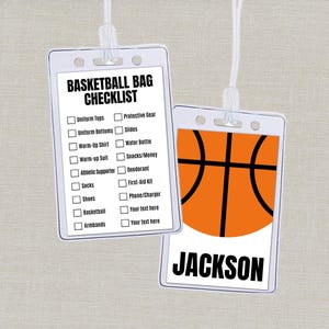 May include: Two white plastic basketball bag tags with white cords. One tag has a checklist with the words "BASKETBALL BAG CHECKLIST" and a list of items. The other tag has an orange basketball graphic and the name "JACKSON" in black.