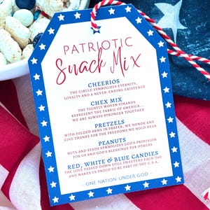 May include: A patriotic snack mix tag in red, white, and blue. The tag lists ingredients: Cheerios, Chex Mix, pretzels, peanuts, and red, white, and blue candies. The tag is tied with red and white string. The text reads 'Patriotic Snack Mix'.