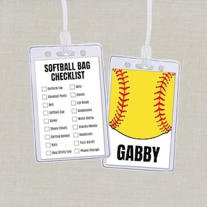 Può includere: Due etichette di plastica trasparente con cordini bianchi. Un'etichetta presenta una lista di controllo per la borsa da softball, l'altra una grafica di softball gialla con cuciture rosse e il nome "Gabby". La lista include articoli come la maglia dell'uniforme e la borraccia.