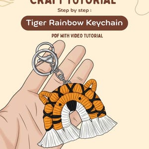 May include: A handmade tiger rainbow keychain with orange, black, and white accents. The keychain is attached to a silver metal ring. The image includes the text "CRAFT TUTORIAL" and "Tiger Rainbow Keychain".