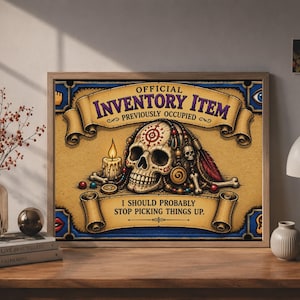 May include: A rectangular framed wall art print featuring a beige background with a central illustration of a human skull adorned with beads and feathers, a lit candle, and bones. The text reads OFFICIAL INVENTORY ITEM PREVIOUSLY OCCUPIED and I SHOULD PROBABLY STOP PICKING THINGS UP in dark blue and black lettering.