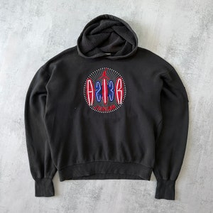 Puede incluir: Sudadera con capucha negra con un logotipo bordado en rojo, blanco y azul que dice "23" y "JORDAN".