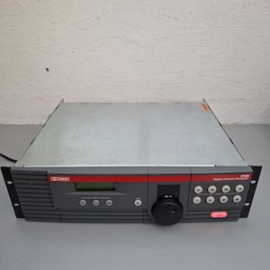 Può includere: Un processore per cinema digitale grigio e nero con una striscia rossa. Il dispositivo ha uno schermo, pulsanti e una grande manopola. Il logo Dolby è visibile sul pannello frontale. Il numero di modello è CP650.