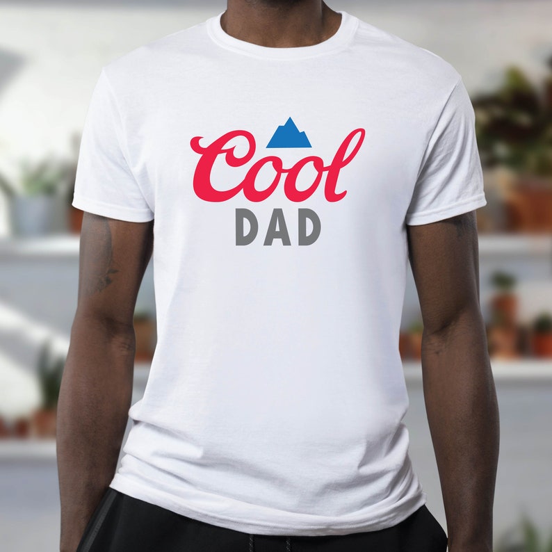 As an example of end use, the Cool Dad logo is shown on a White shirt. Cool is in red, Dad is in gray, and there is a blue mountain shape above the Cool text.