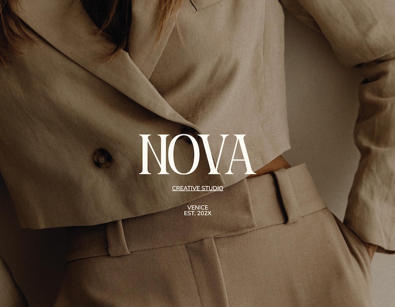May include: A beige suit jacket with a two-button closure and matching high-waisted trousers. The text "NOVA CREATIVE STUDIO VENICE EST. 202X" is displayed in white. The outfit is made of a textured fabric.
