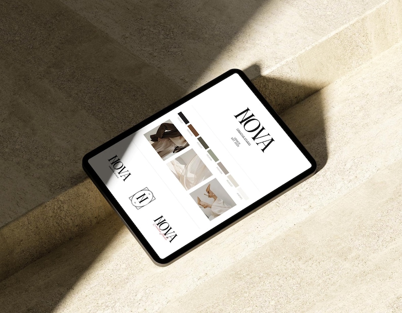 May include: A black tablet displaying the "NOVA Creative Studio" logo and design samples. The screen shows a logo, color palette, and images. The tablet is angled on a light-colored surface, with shadows.