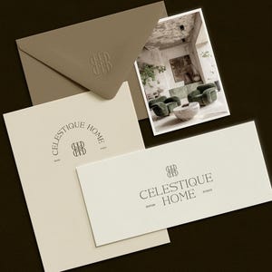 May include: An assortment of stationery items, including an envelope, a postcard, and two cards, arranged on a dark surface. The items feature the logo "CELESTIQUE HOME STUDIO" in a minimalist design. The postcard displays a room interior.