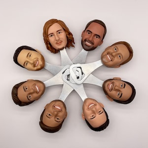 May include: A set of seven bottle openers featuring different faces. Each opener is made of metal and has a silver finish. The faces are all different and have unique expressions.