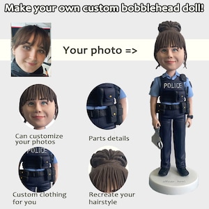 May include: A custom bobblehead doll with a police uniform, a blue shirt with the word "POLICE" on it, a black belt, and a black vest. The doll has brown hair in a bun and a neutral facial expression. The doll is standing on a white base with the words "officer Aurel" written on it.