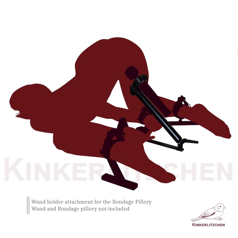 May include: A black wand holder attachment for the Bondage Pillory. The image shows a silhouette of a person in a bondage position. The text on the image reads "KINKERLITZCHEN" and "Wand holder attachment for the Bondage Pillory. Wand and Bondage pillory not included."