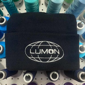 May include: Black beanie with a white embroidered logo of a globe with the word "LUMON" inside.