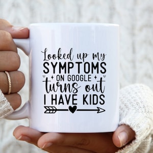 May include: White ceramic mug with black text that reads "Looked up my SYMPTOMS on GOOGLE turns out I HAVE KIDS" with a black arrow and heart.