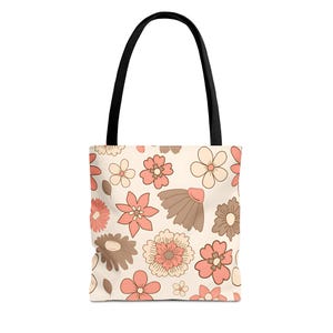 May include: A beige tote bag with a floral pattern. The flowers are in shades of peach, brown, and cream. The bag has black handles.