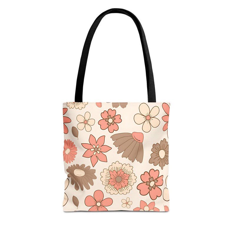 May include: A beige tote bag with a floral pattern. The flowers are in shades of peach, brown, and cream. The bag has black handles.