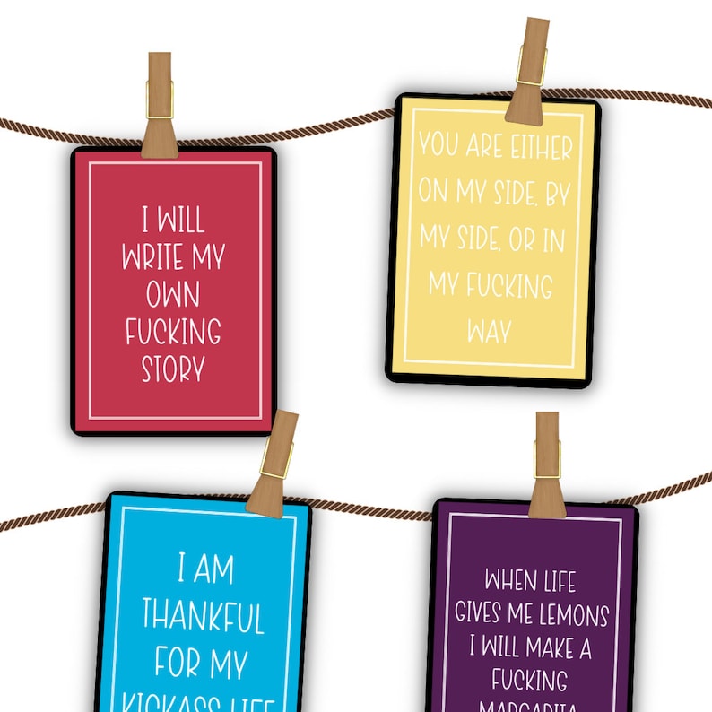 Puede incluir: Cuatro tarjetas coloridas con citas inspiradoras colgadas en un tendedero. Las citas son: "Escribir&eacute; mi propia historia de mierda", "Est&aacute;s o bien de mi lado, o a mi lado, o en mi camino de mierda", "Estoy agradecido por mi vida de mierda", y "Cuando la vida me da limones, har&eacute; una margarita de mierda".