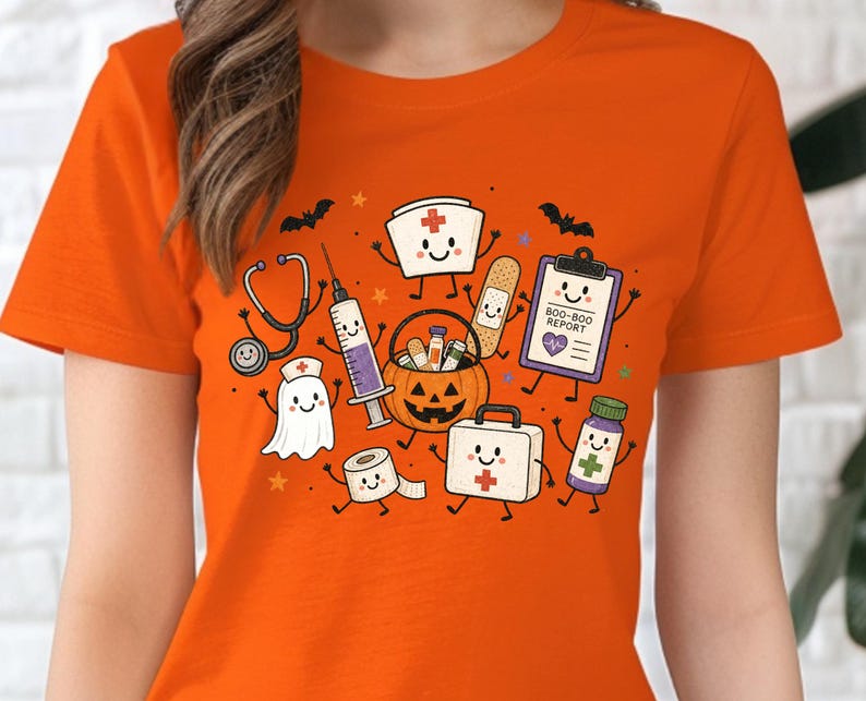 May include: An orange t-shirt featuring a graphic print of various medical-themed characters including a stethoscope, syringe, ghost, bandage, clipboard labeled BOO-BOO REPORT, pumpkin bucket, roll of tape, first aid kit, and medicine bottle.