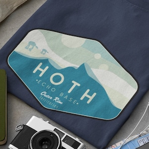 Könnte beinhalten: Ein marineblaues T-Shirt mit einer Vintage-Grafik einer schneebedeckten Bergkette mit dem Text "HOTH - ECHO BASE - Outer Rim Territories".