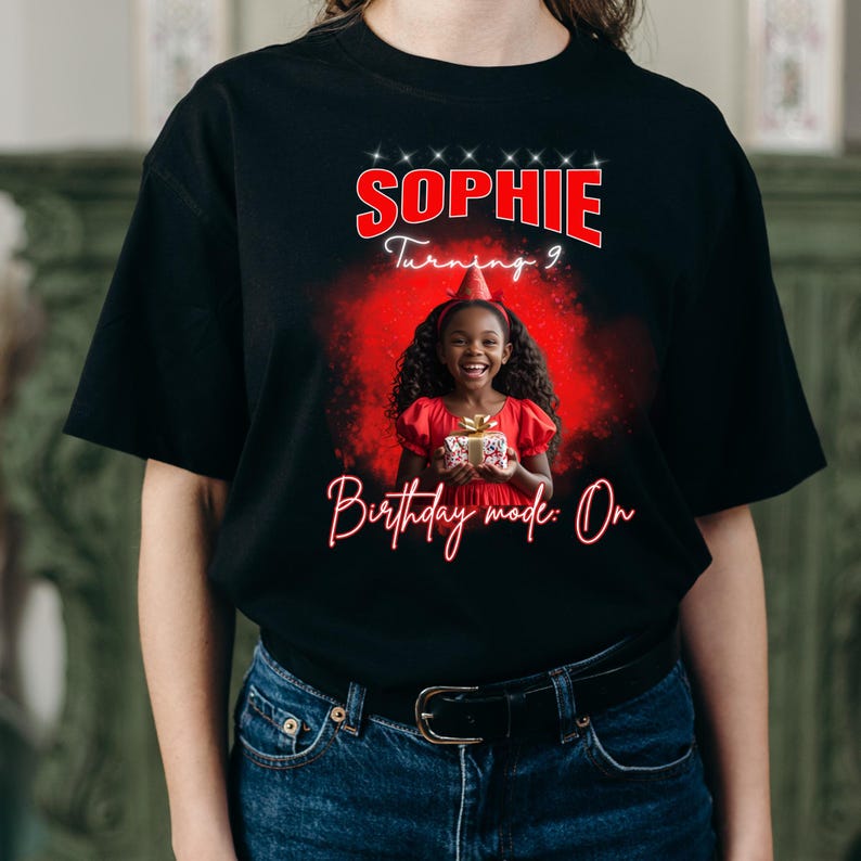 Może przedstawiać: Czarny t-shirt z czerwoną grafiką z napisem "Sophie Turning 9" i "Birthday mode: On". Grafika zawiera zdjęcie uśmiechniętej dziewczynki w czerwonej sukience trzymającej prezent, na urodziny.