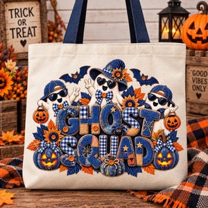 May include: A cream-colored canvas tote bag with dark blue handles featuring a graphic of three ghosts wearing sunglasses and hats. The text GHOST SQUAD is printed in blue plaid letters, surrounded by orange pumpkins, sunflowers, and bats.