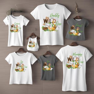 May include: Set of six white and grey t-shirts with a jungle animal theme. The shirts feature the text "Daddy of the Wild One", "Mummy of the Wild One", "Sis of the Wild One", "Bro of the Wild One", "Cousin of the Wild One", and "Friend of the Wild One".