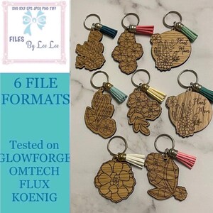 May include: Eight wooden keychains with different designs, including cacti, flowers, and the text "Plant Mom". Each keychain has a small tassel attached.