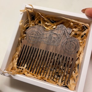 May include: A wooden comb with a motorcycle design carved into the handle. The comb is in a white box with brown packing paper.