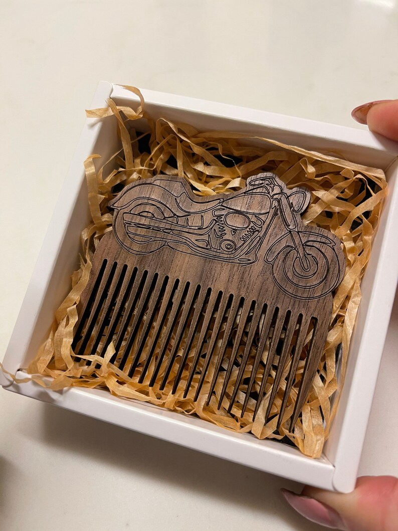 May include: A wooden comb with a motorcycle design carved into the handle. The comb is in a white box with brown packing paper.