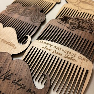 May include: Four wooden combs with different designs, including a mustache, a motorcycle, a truck, and a fish. The combs are engraved with the text "Happy Father's Day Love from Ethan".