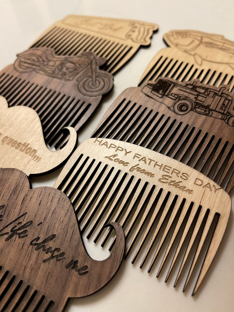 May include: Four wooden combs with different designs, including a mustache, a motorcycle, a truck, and a fish. The combs are engraved with the text "Happy Father's Day Love from Ethan".
