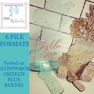 May include: A set of six table number signs for a wedding or special event. The signs are made of wood and glass and feature a mason jar design with floral accents. The numbers are written in gold script and the text "Table One" is visible on two of the signs. The signs are tested on Glowforge, Omtech, Flux, and Koenig.